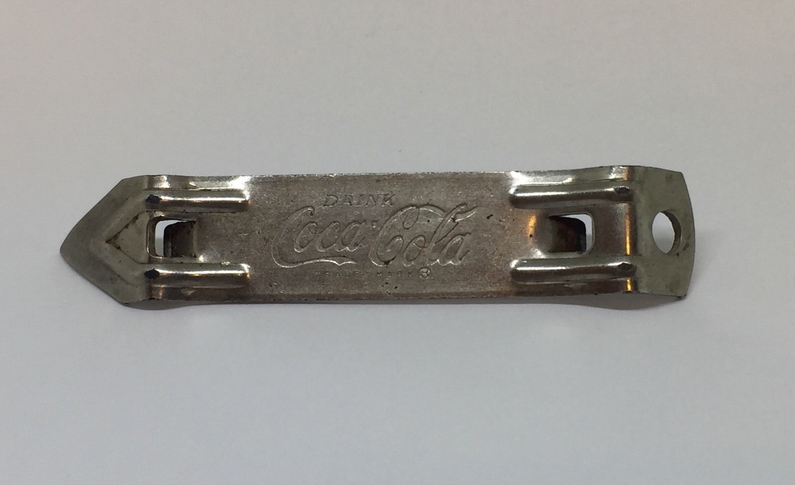 Foto van ouderwetse opener voor drankblikjes. Bron Antiquesnavigator.com: https://www.antiquesnavigator.com/d-2655844/vintage-coca-cola-can-bottle-opener-ekco-chicago.html